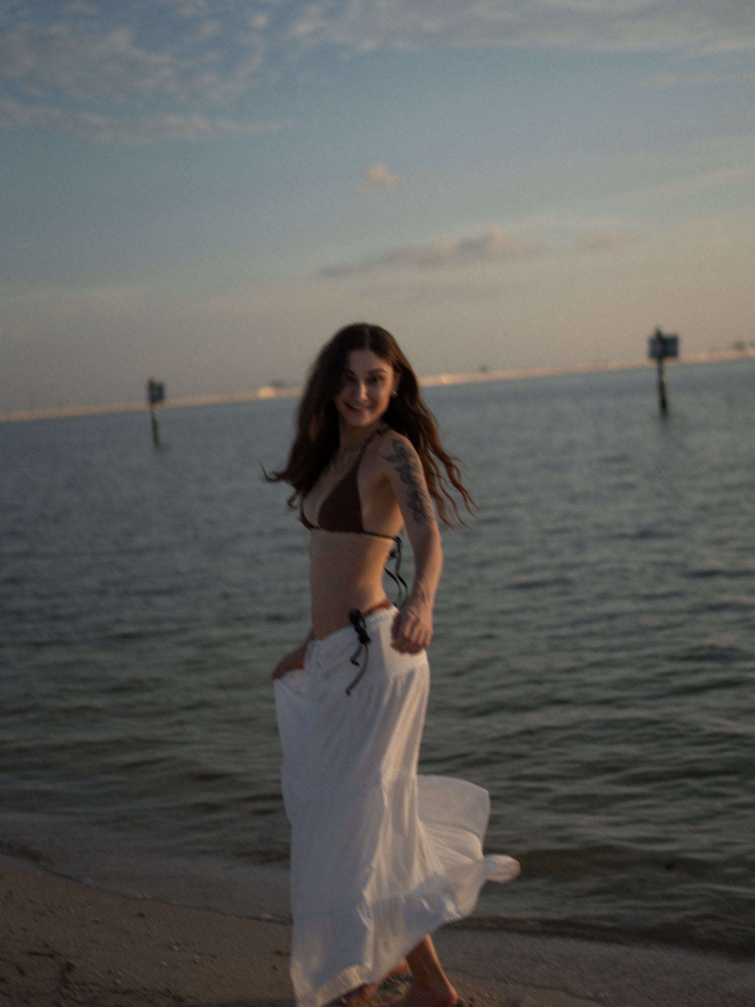 A woman looking back while walking along the shore