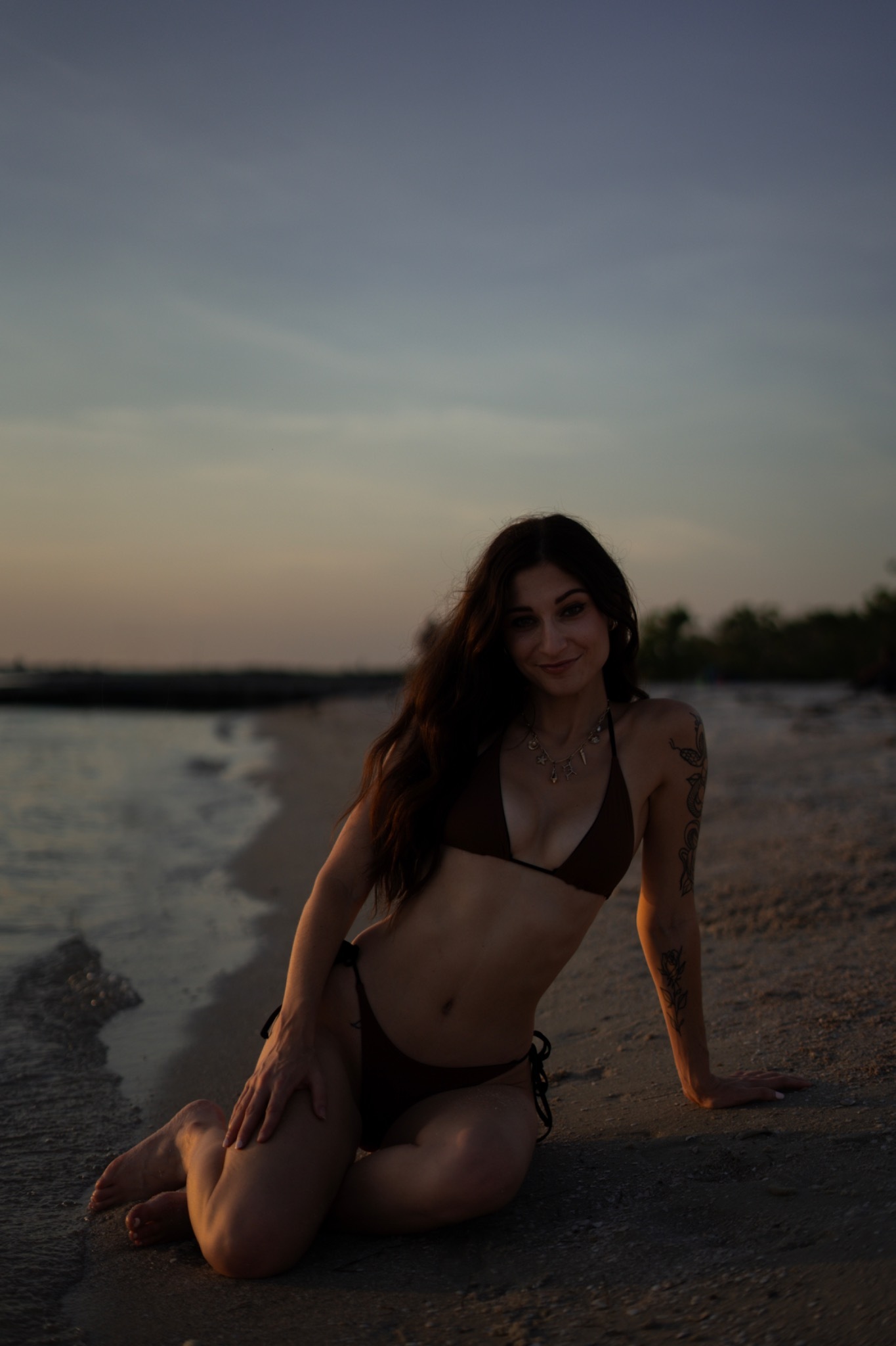 Lindy seated at the edge of the ocean at dusk