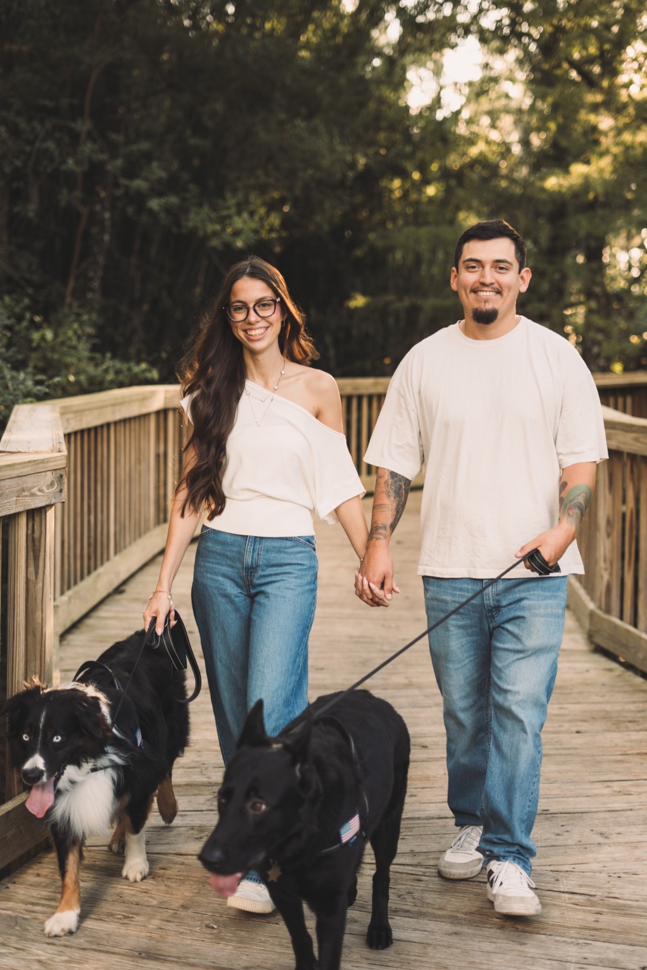 A couple walking their two dogs on a wooded boardwalk