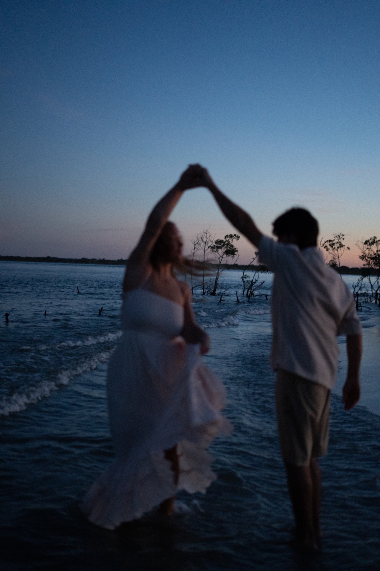 A couple dancing in the ocean at dusk